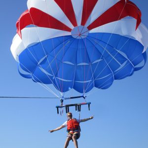 a person flying through the air while holding a blue umbrella