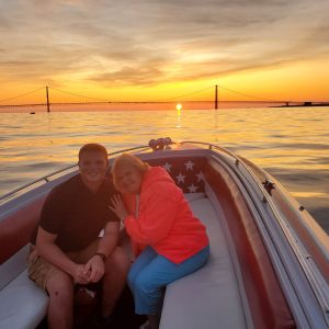 a man and a woman sitting on a beach near a body of water