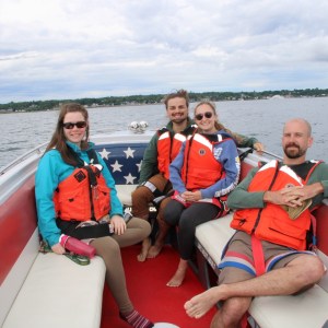 Four people in life vests relaxing on a boat with an American flag motif.