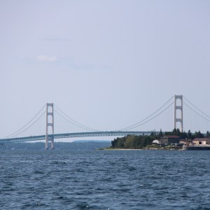 Suspension bridge over a large body of water with trees on the right.