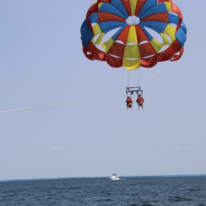 Two people parasailing over the ocean with a colorful parachute.